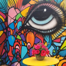 Pink rose bouquet in a gold vase on a yellow table