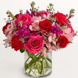 Bouquet of pink and red roses with alstroemeria in a clear glass vase