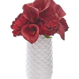 Red calla lilies and roses in a white textured vase