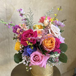 Colorful mixed bouquet of roses and small accent flowers in a gold box