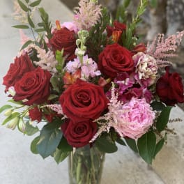 Bouquet of red roses and pink flowers in a clear glass vase