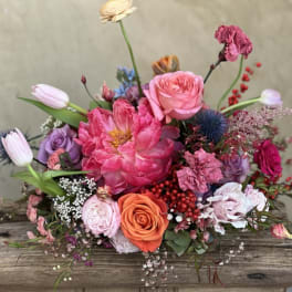 Mixed bouquet of pink, purple, and orange flowers on a wooden surface