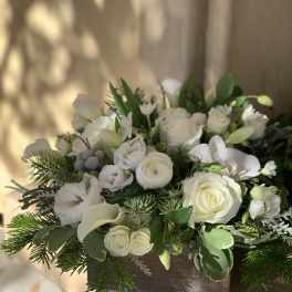 White floral arrangement in a wooden box with roses and calla lilies