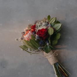 Hand-tied bouquet with red roses and a pink protea