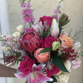 Hand-tied bouquet with pink roses, lilies, and a protea