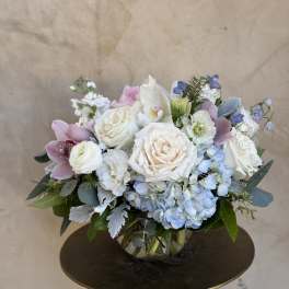 Pastel bouquet of roses, hydrangeas, and orchids in a glass vase