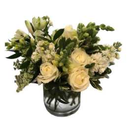 Cream roses and white flowers arranged in a glass vase