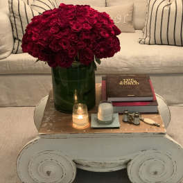 Large bouquet of deep red roses in a green vase on a coffee table