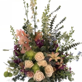 Tall mixed floral arrangement with peach roses and lilies in a white vase