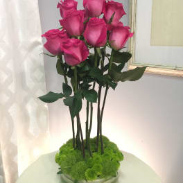 Pink roses arranged in a low glass vase with green moss