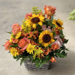 Basket of sunflowers, roses, and orange mixed blooms