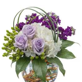 Lavender roses and white hydrangea in a glass vase with purple flowers