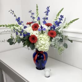 Blue vase with red gerberas, white hydrangeas, and blue delphinium
