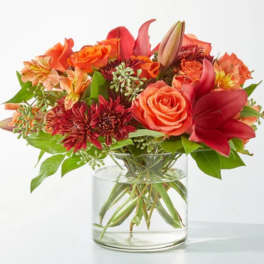Orange and red mixed bouquet in a clear glass vase