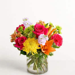 Mixed bouquet of roses, lilies, and chrysanthemums in a glass vase