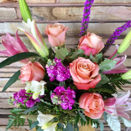 Bouquet of peach roses, lilies, and purple accent flowers