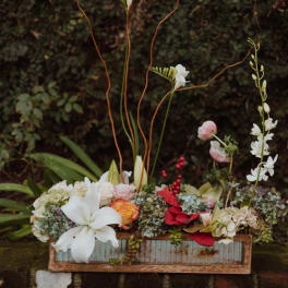 Mixed floral arrangement in a rustic wooden box with tall stems