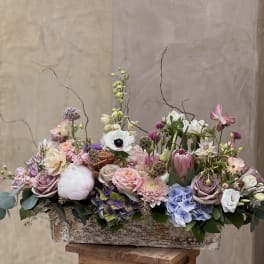 Mixed pastel floral arrangement in a rustic rectangular container