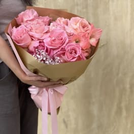 Pink rose bouquet wrapped in brown paper with a pink ribbon