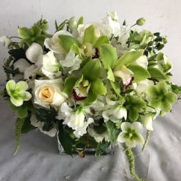 White and green floral arrangement in a square glass vase
