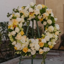 Large floral wreath of white and yellow flowers on a stand