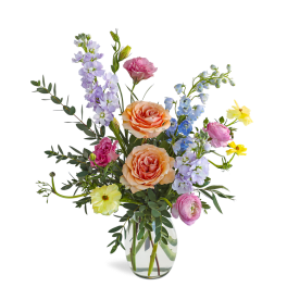 Mixed pastel flower arrangement with peach roses and assorted blooms in a clear glass vase