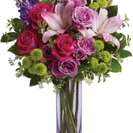 Bouquet of pink and purple flowers in a tall glass vase