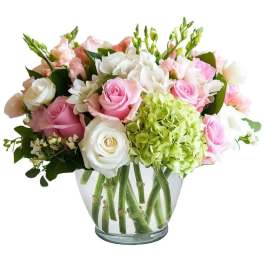 Pink and white roses with green hydrangea in a glass vase
