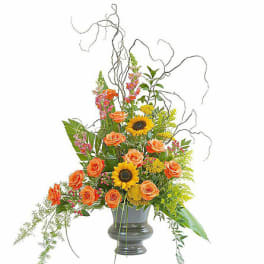 Orange roses and sunflowers in a gray vase with curly branches