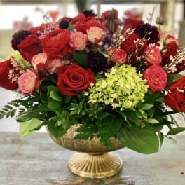 Red and pink roses arranged in a gold pedestal bowl