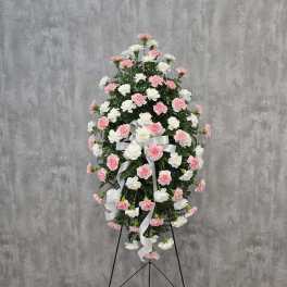 Standing floral spray of pink and white carnations with a white ribbon