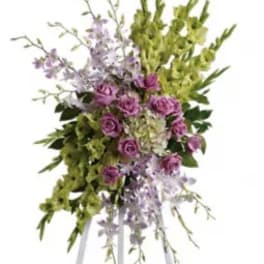 Tall floral spray with purple roses and green blooms on a white stand