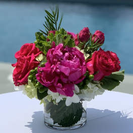Pink roses and a magenta peony in a clear glass vase