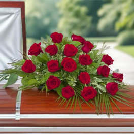Red rose casket spray on a polished wooden coffin