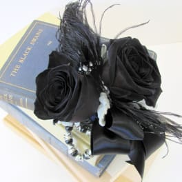 Black rose arrangement with feathers and beads on a book box
