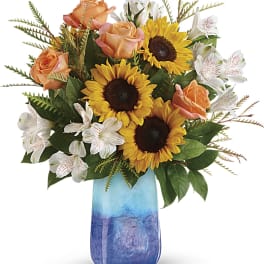 Bouquet of sunflowers, peach roses, and white alstroemeria in a blue vase