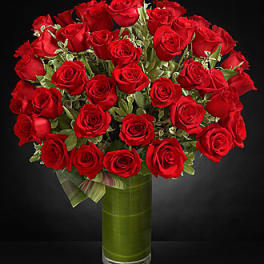 Bouquet of red roses in a tall green glass vase