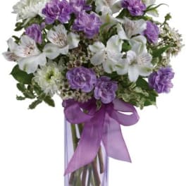 Purple and white bouquet in a clear glass vase with a purple ribbon