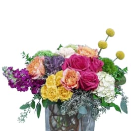 Colorful mixed flower arrangement in a square glass vase