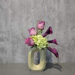 Pink roses and purple calla lilies in a cream ceramic vase