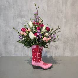 Bouquet of pink, white, and purple flowers arranged in a pink cowboy boot vase