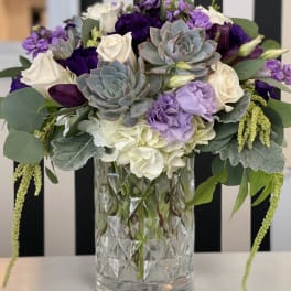 Purple and white floral arrangement in a clear glass vase