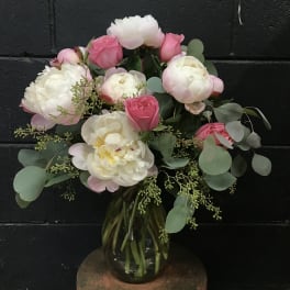 Pink and white peonies and roses in a glass vase