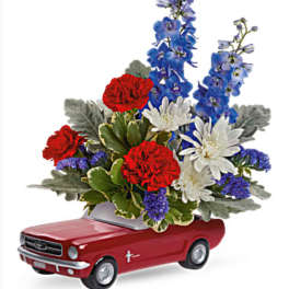 Red toy car topped with red, white, and blue flowers