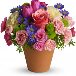 Mixed bouquet of pink, purple, and white flowers in a brown pot