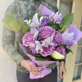 Bouquet of pink roses and lilies wrapped in lavender paper