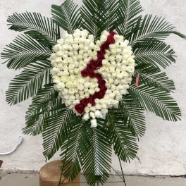 Heart-shaped rose wreath with white and red roses on a stand