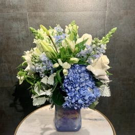 Blue hydrangeas and white lilies in a glass vase