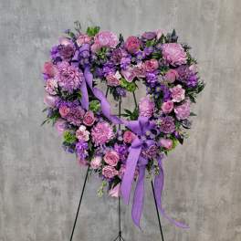 Purple and pink floral wreath on a stand with ribbon bows