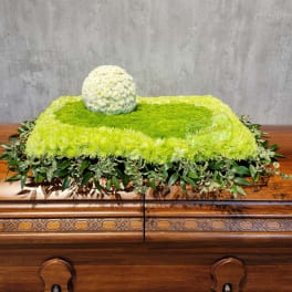 Green and white floral casket spray with a round white flower cluster